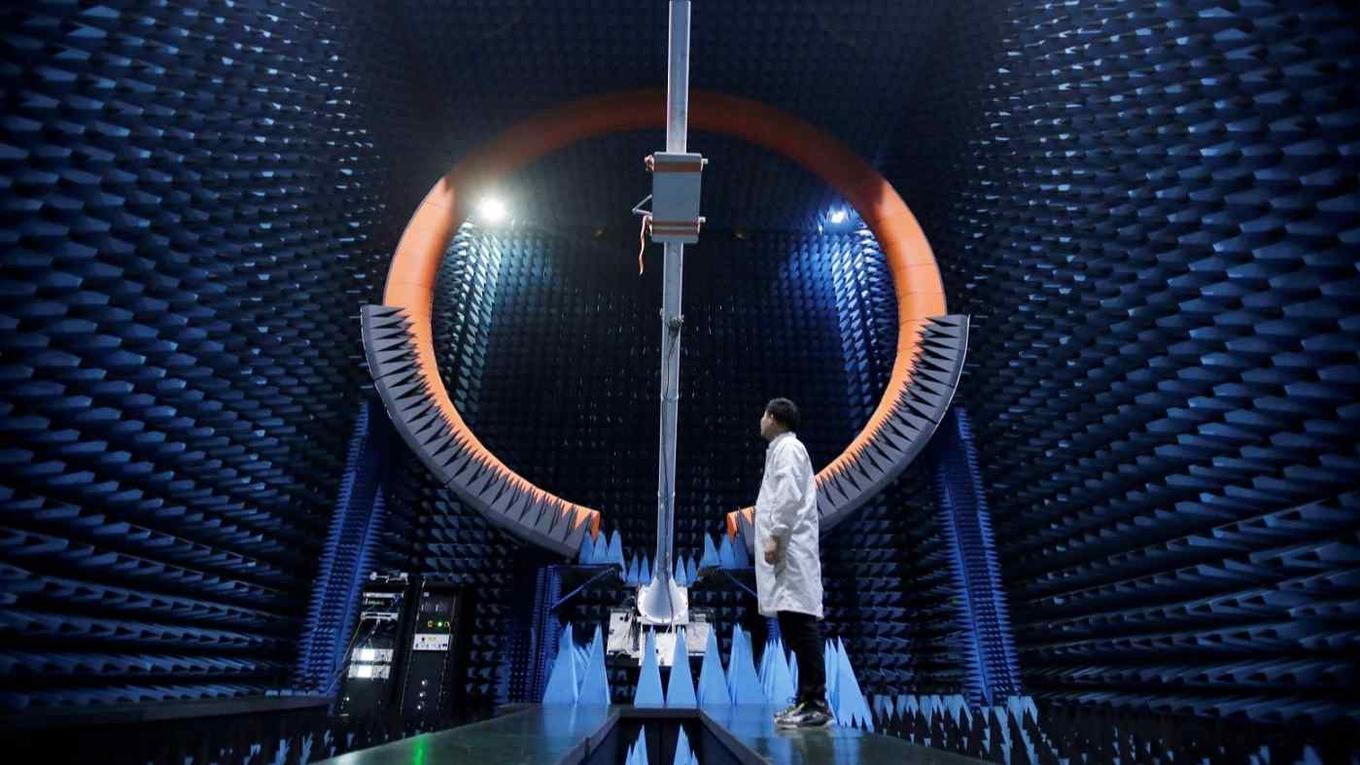 Một kỹ sư đứng dưới ăng-ten 5G của trạm gốc tại trung tâm sản xuất Huawei ở Đông Quan, Trung Quốc.