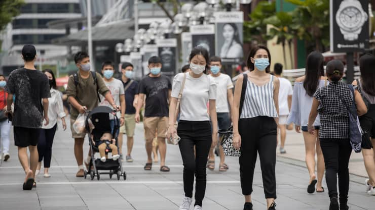 People wearing face masks as a precaution walking along Orchard Road, a famous shopping district in Singapore.