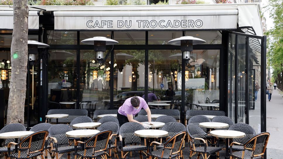 Một nhân viên của quán "Café du Trocadéro" ở Paris lau bàn ghế vào ngày 11/5. Ảnh: AFP