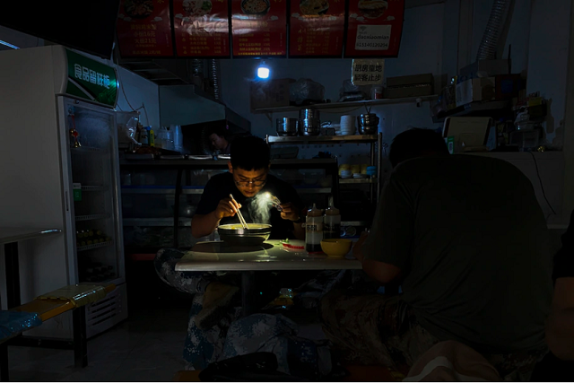 Người dân ở Trung Quốc phải ăn sáng dưới ánh đèn flash của điện thoại. Ảnh: AP.