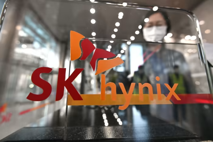 A woman wearing a face mask looks through a glass door with the SK Hynix logo on it